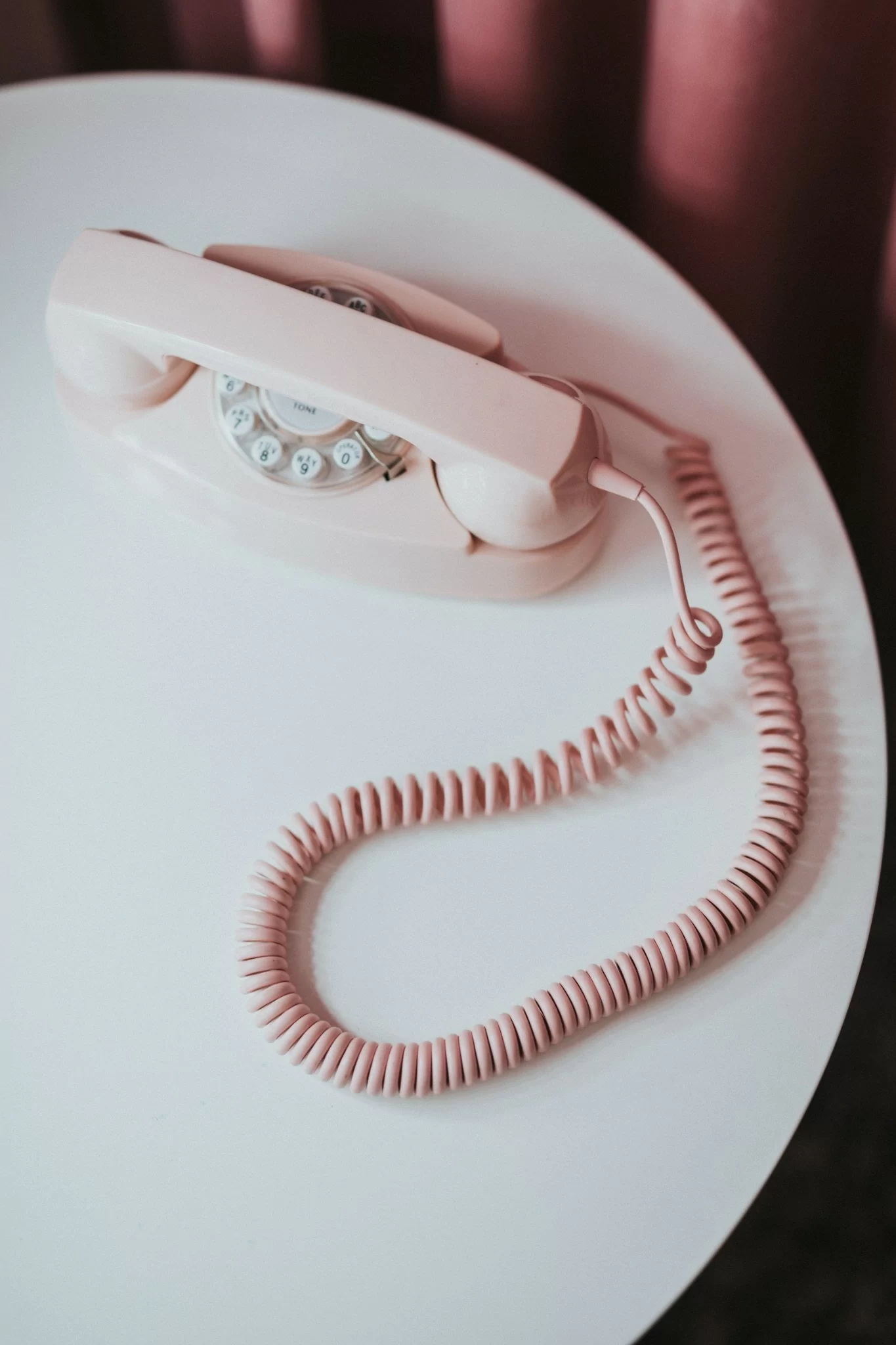 Pink rotary telephone on a white table